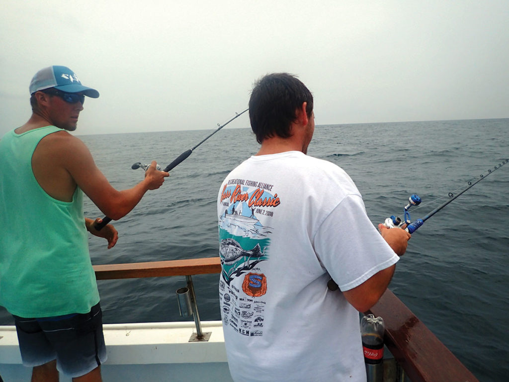 Two men in a boat on holding fishing rods
