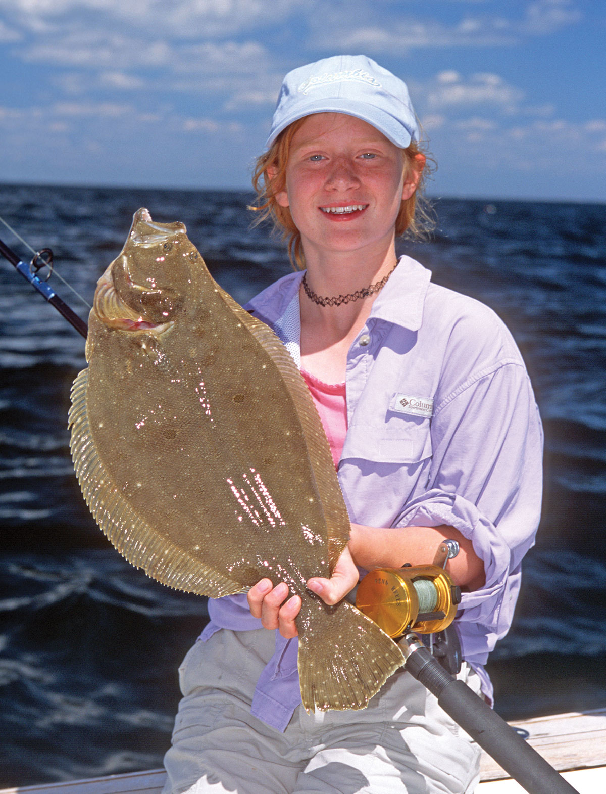 Girl on a boat showing off the fluke fish she caught