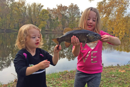 Two girls showing off a black fish