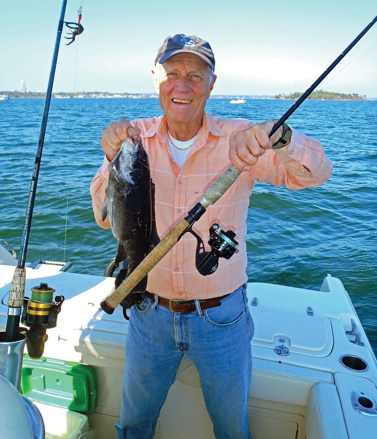 Man holding a fishing rod and a black fish in a boat