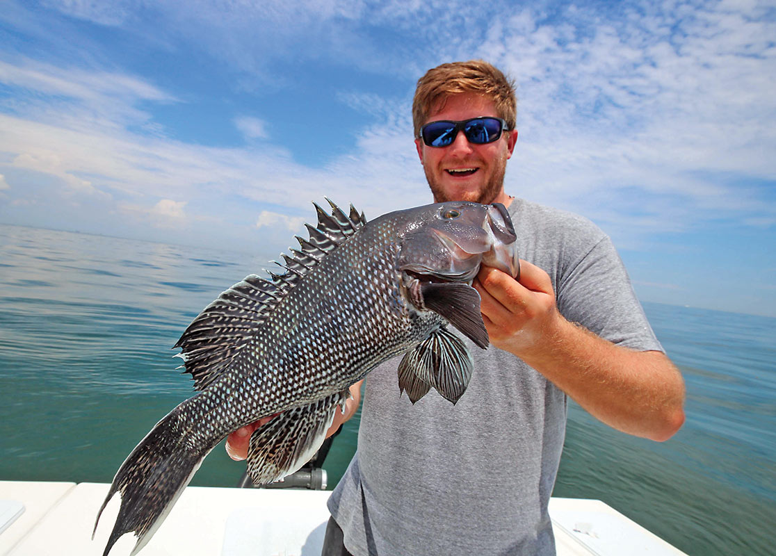 Man on a boat showing off his black sea bass