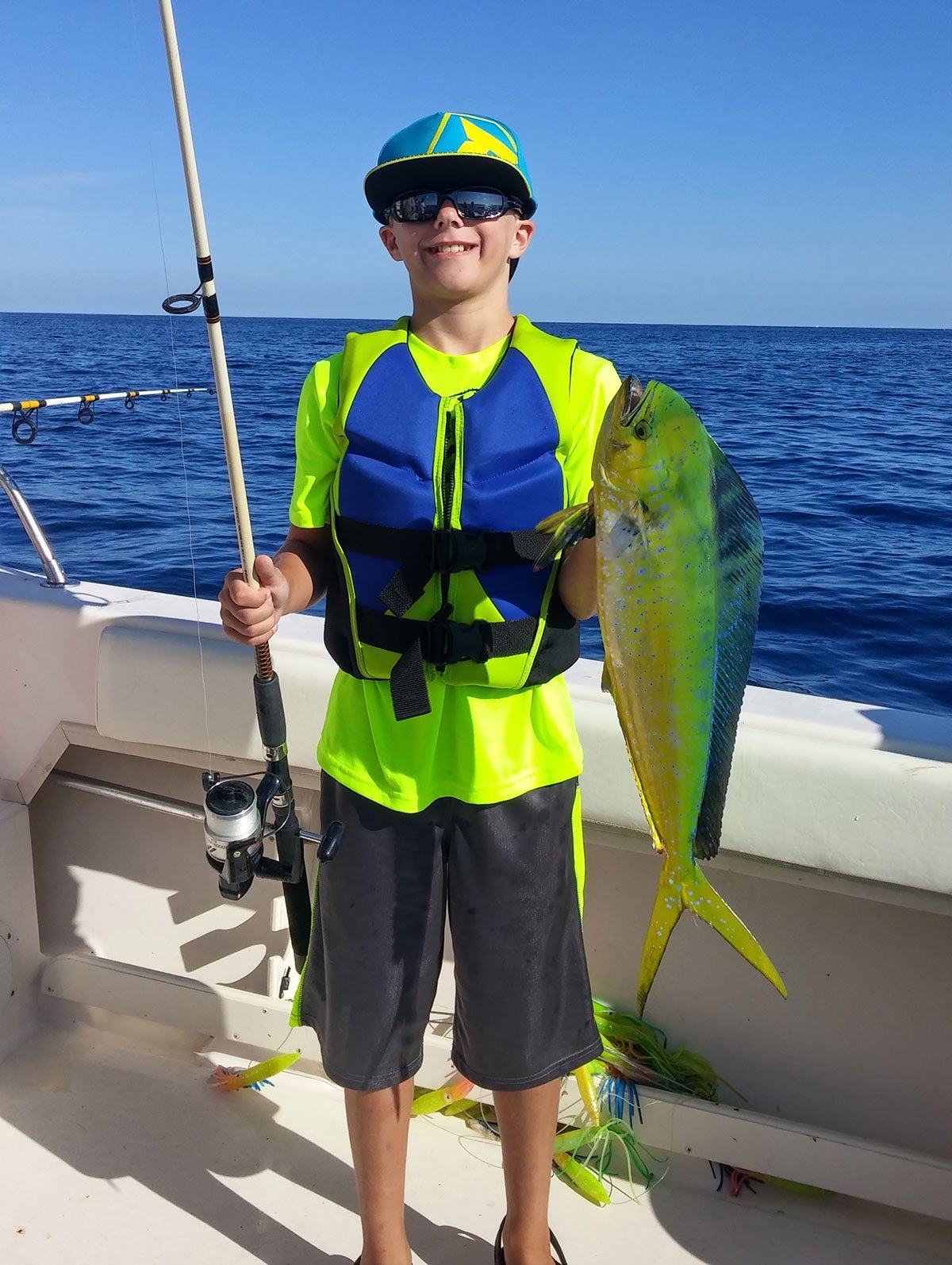 kids on a boat holding his fish and rod