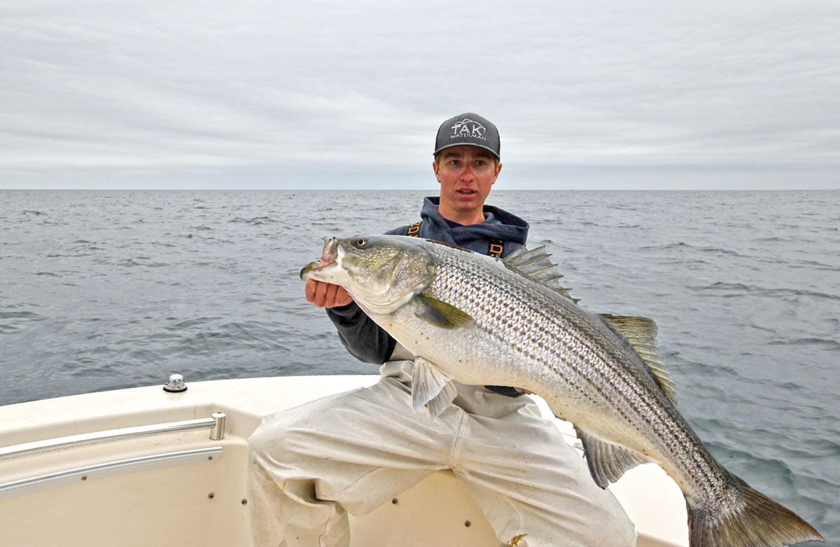 Man in a boat showing off his striped bass