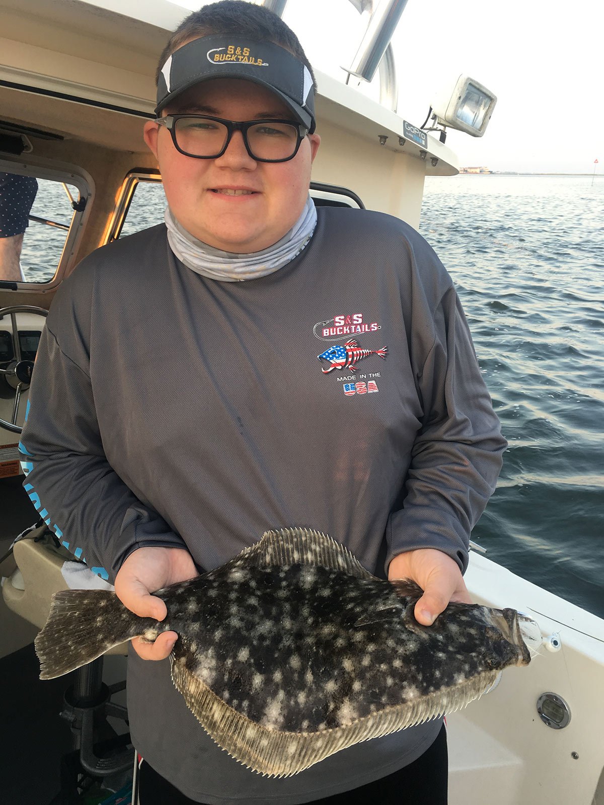 Boy in cap showing off fluke fish he caught