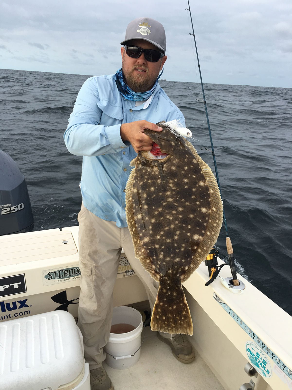 Brett Taylor in a boat showing off his doormat fluke fish he caught