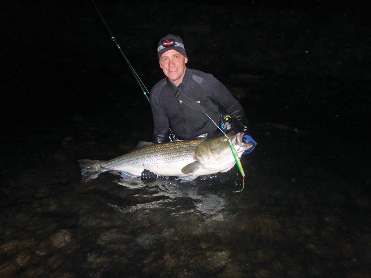 Man on the beach at night holding a needlefish