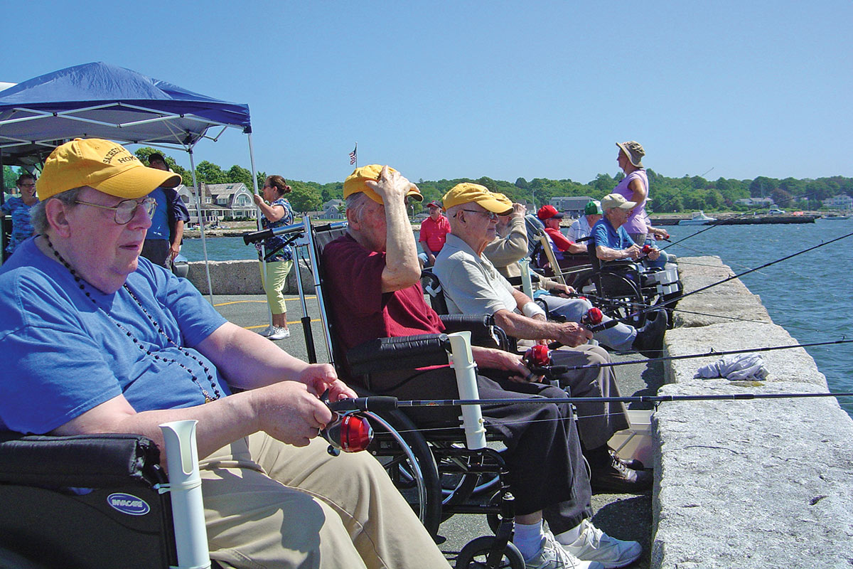 Group of senior citizens in wheelchair from the Sacred Heart Nursing Home enjoying fishing off a pier