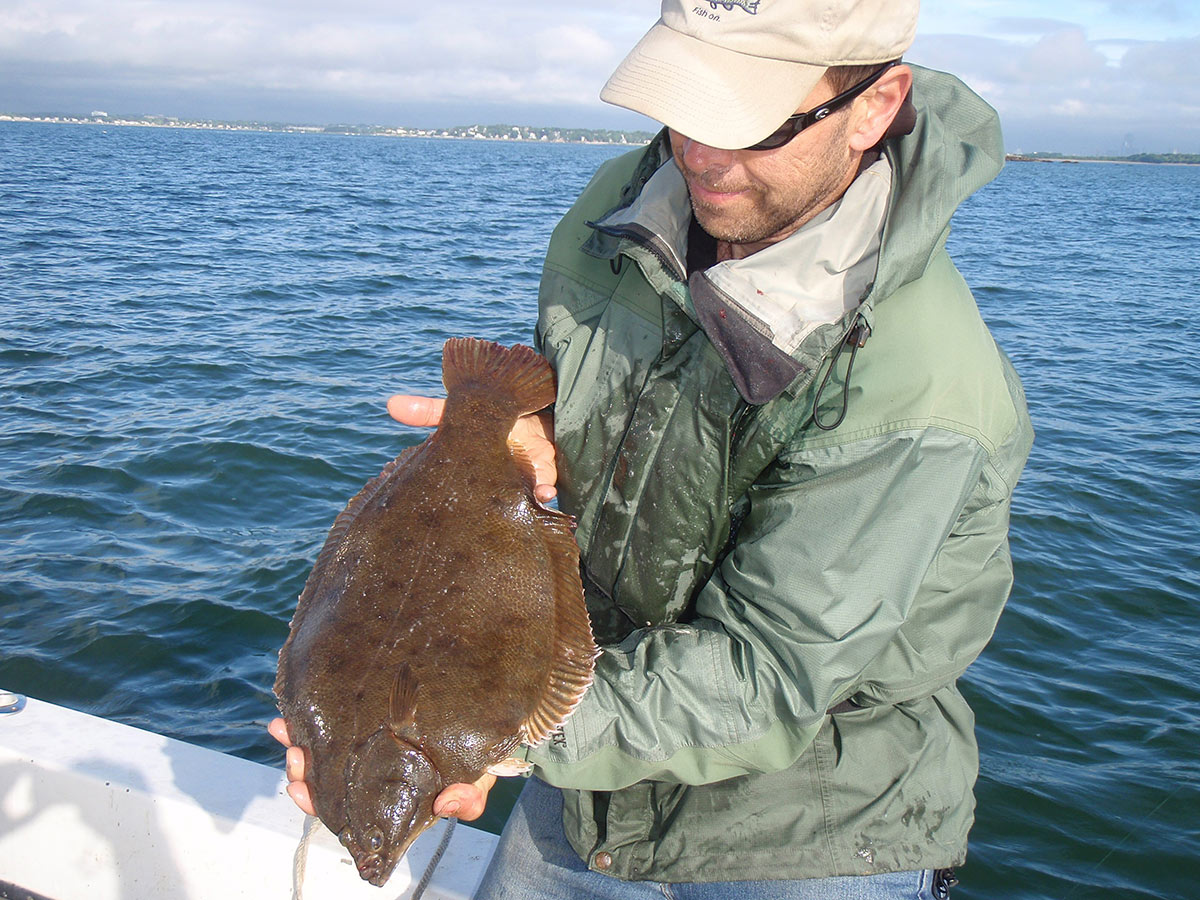 man in cap showing the flounder fish he caught