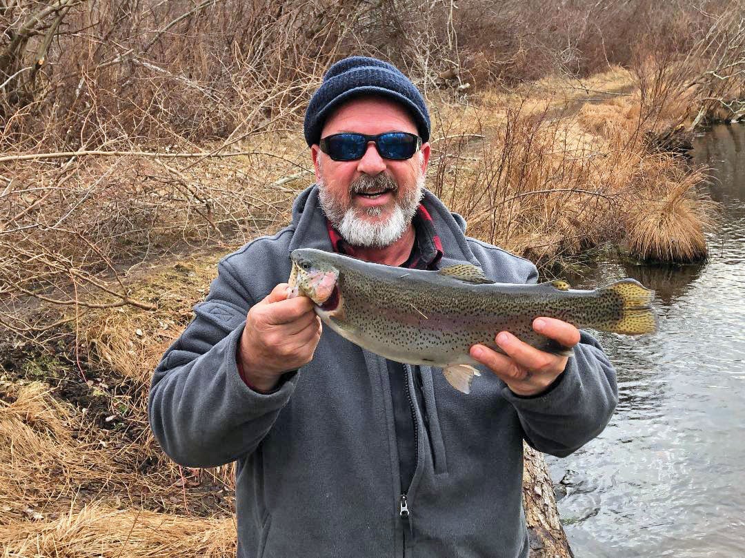 man with cap and sunglasses showing his trout fish