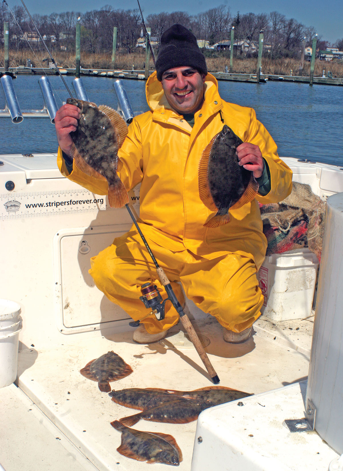 man in yellow in a boat showing off his flounder fish
