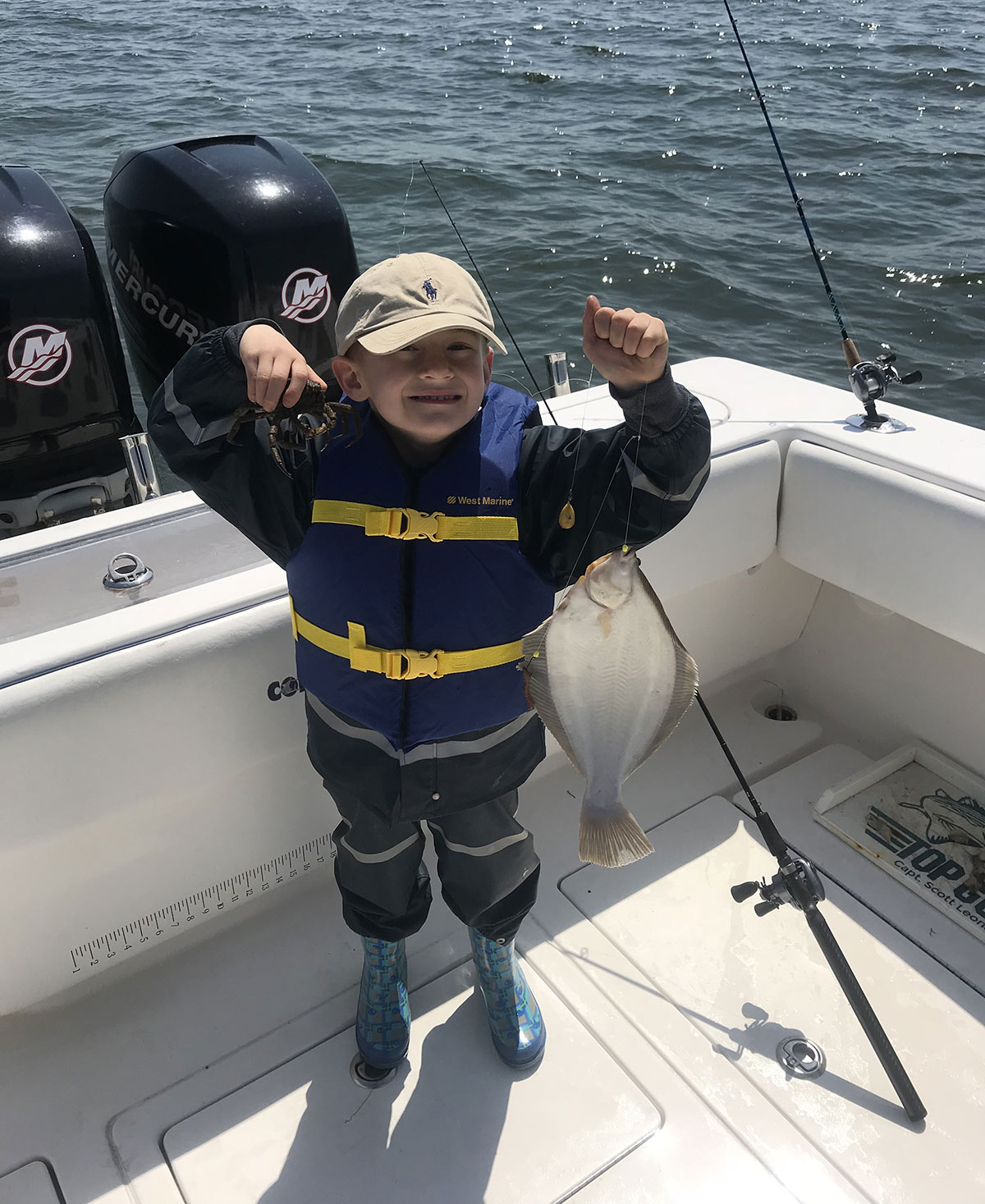 child on a boat showing off his flounder fish attached to aline