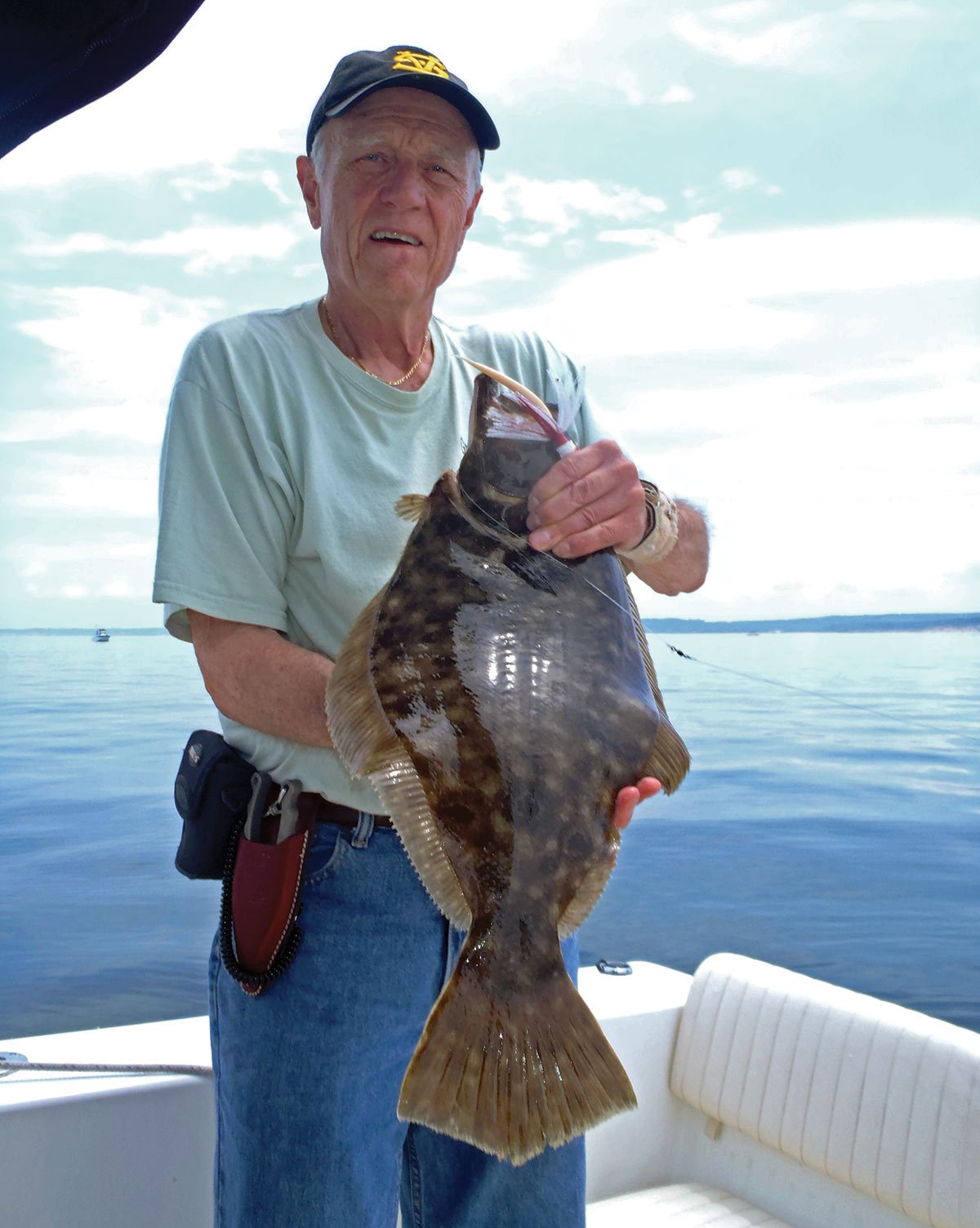 Man on a boat holding a fluke fish