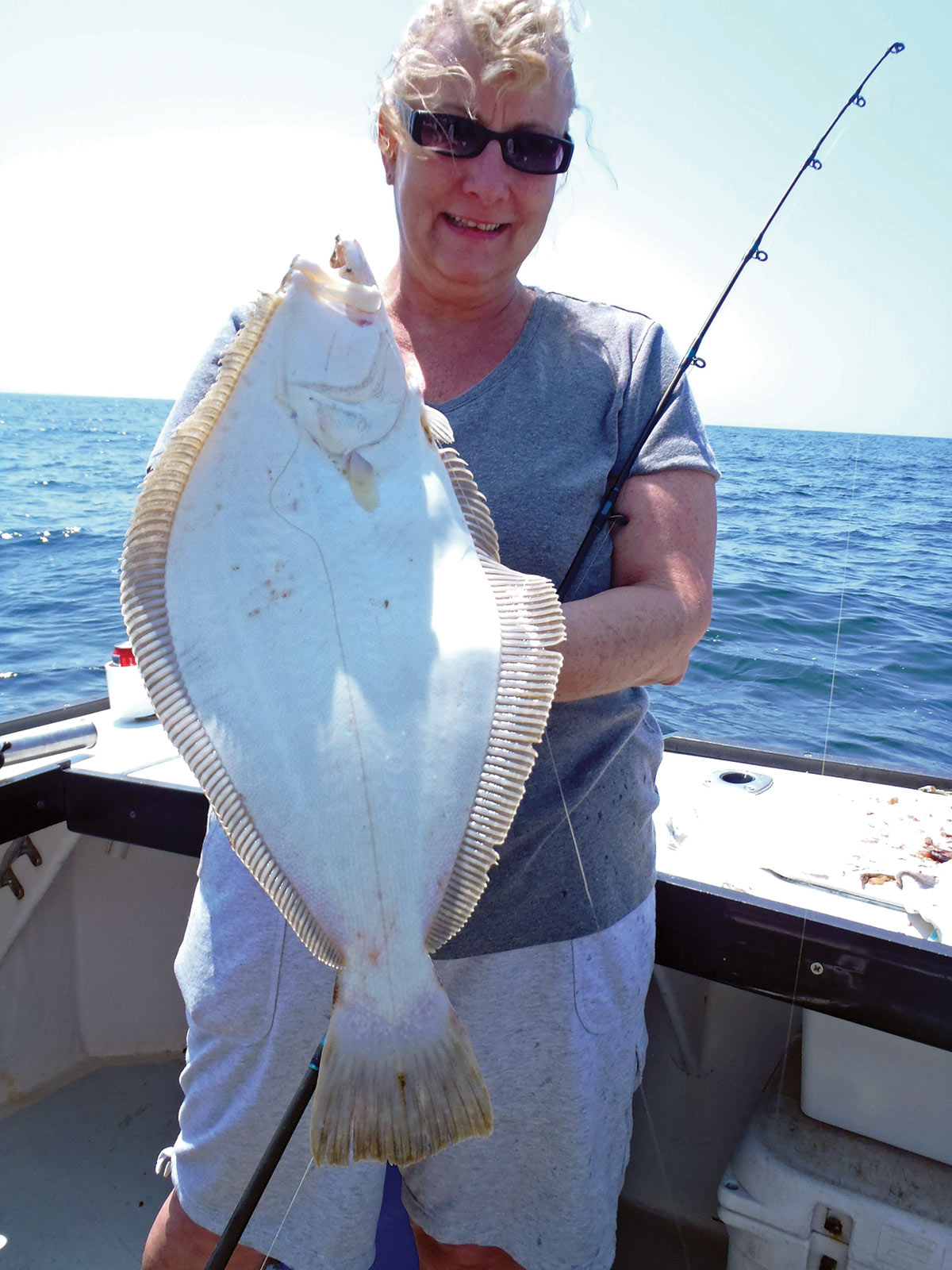 Woman on a boat showing her fluke fish