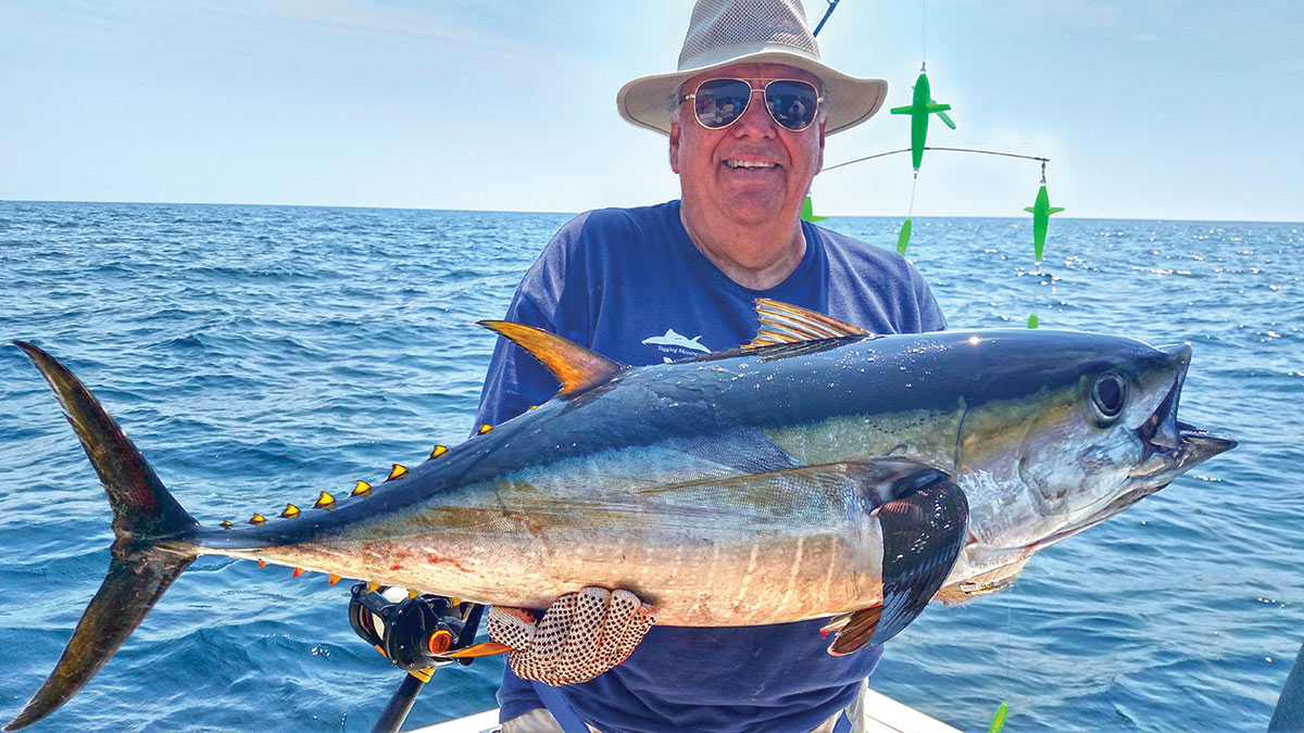 Man in a bat at sea showing off his yellowfin tuna catch