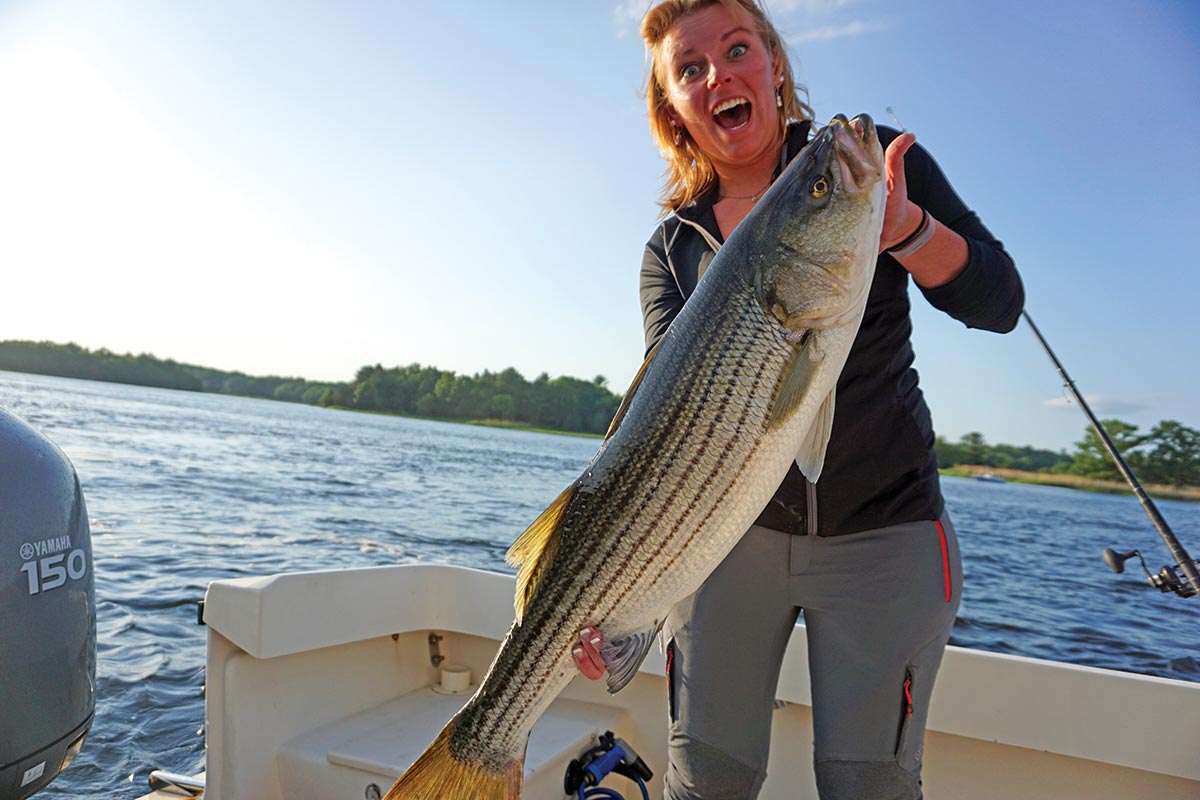 Woman happily shows off a huge striped bass