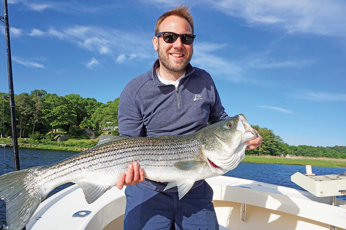 Man in glasses showing off a huge striped bass
