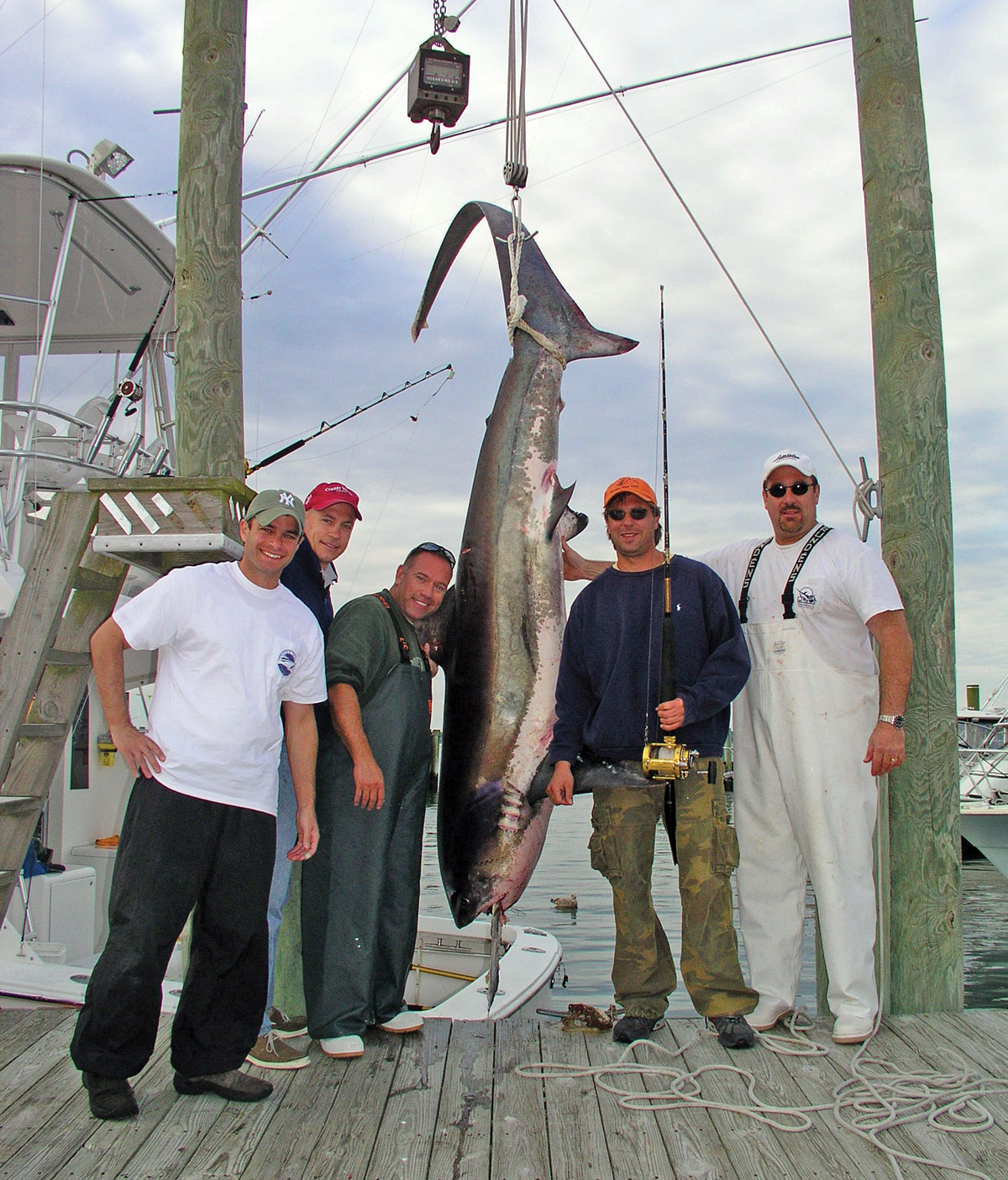 five men showing off their catch hanging off a line