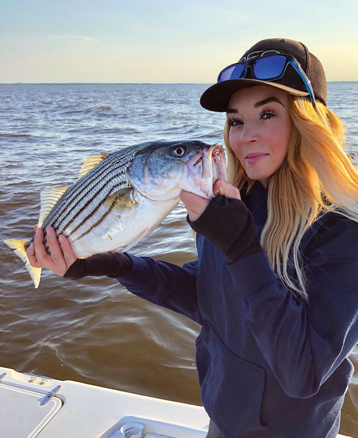 Blond woman shows off striped bass