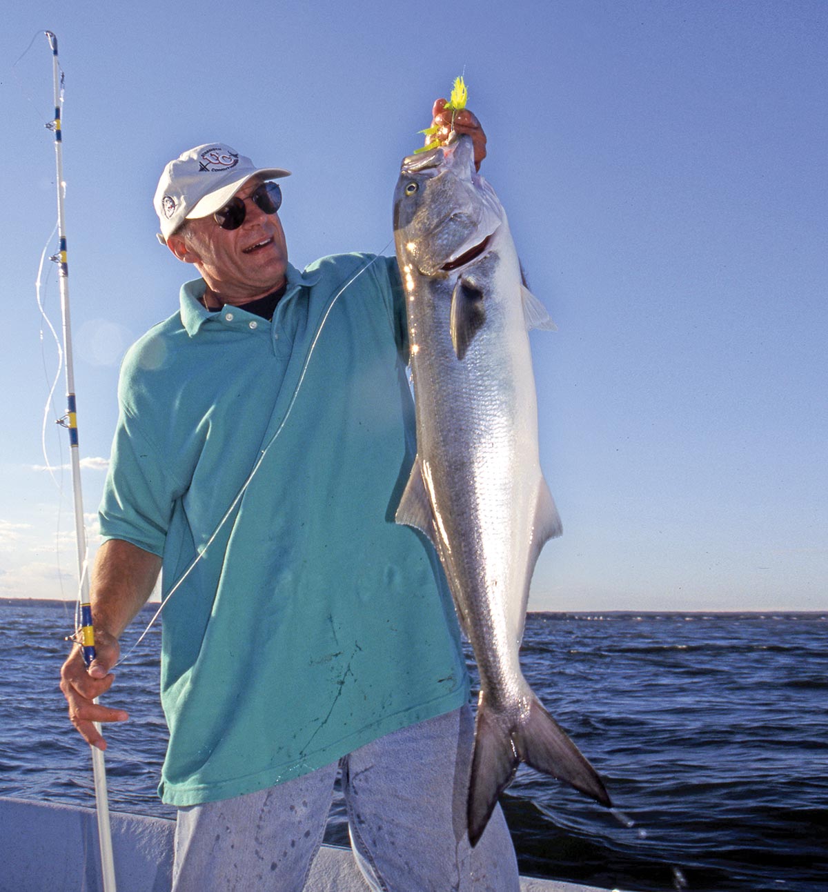 Man holding up a huge fish and a rod