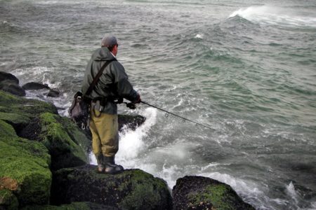 Man fishing using a rod standing on the rocks