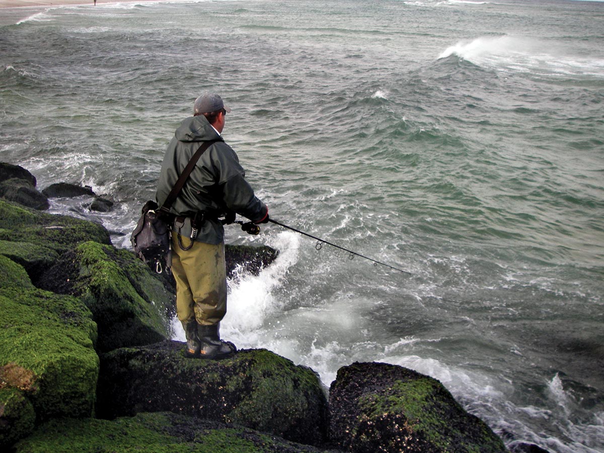 Man fishing using a rod standing on the rocks