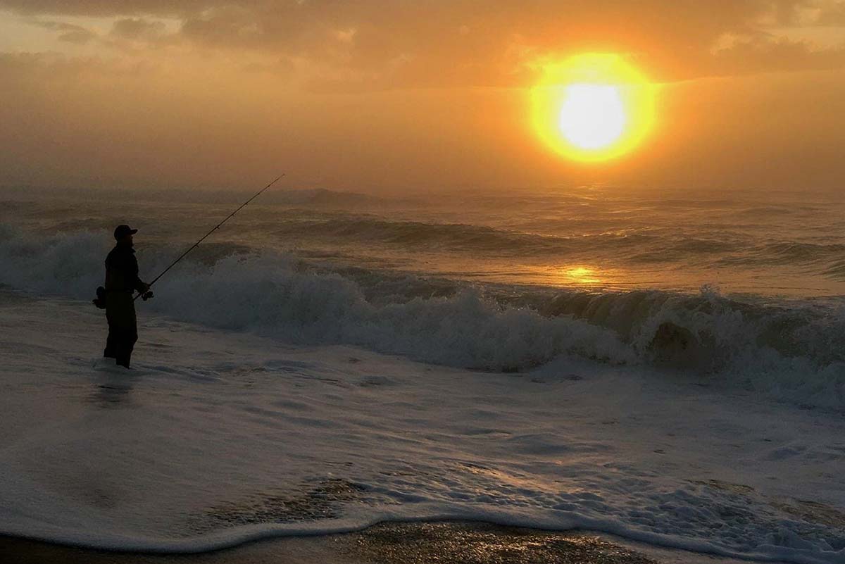 Woman Saltwater Fishing Casting from Boat during Sunrise Stock